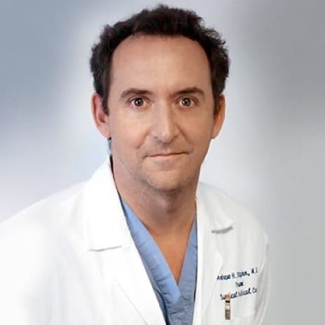 Portrait of Dr. Andrew H. Stephen in white medical coat & blue scrubs