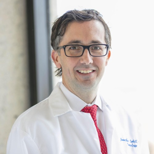 Dr. Jonathan Cahill stadning with white coat and red tie