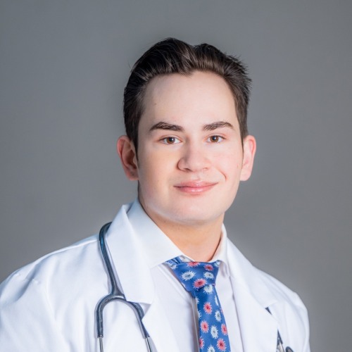 Alexander Pralea headshot, grey background, white coat, blue tie with stethoscope