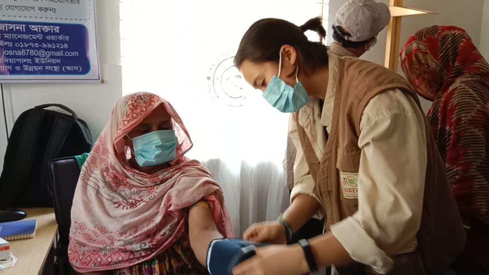 Alex is measuring a patient's blood pressure at Mohajonpara Community Clinic, Holdiapalong, Ukhiya, Cox's Bazar.