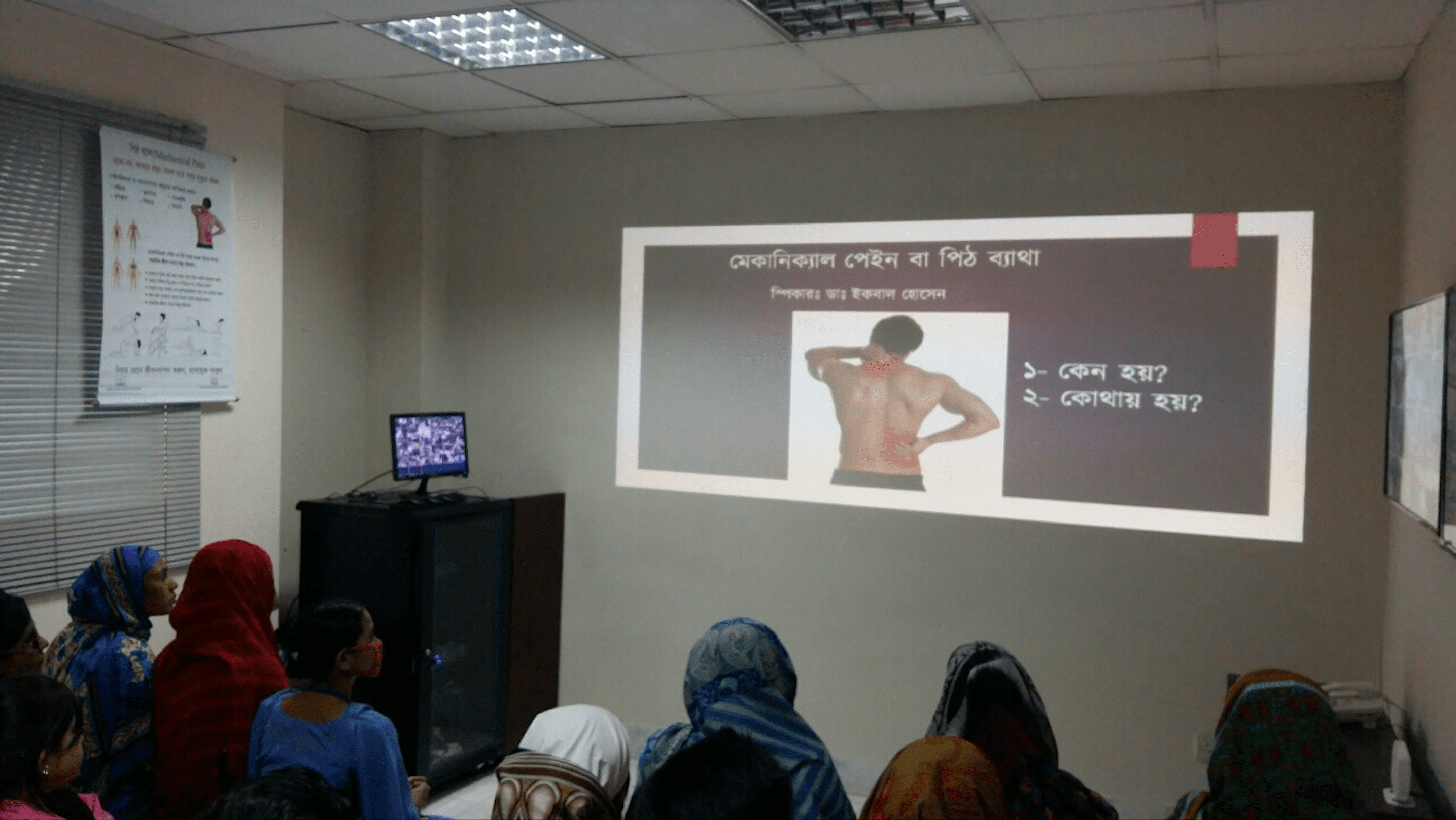 People attending a workshop, looking at a photo of a man with neck pain